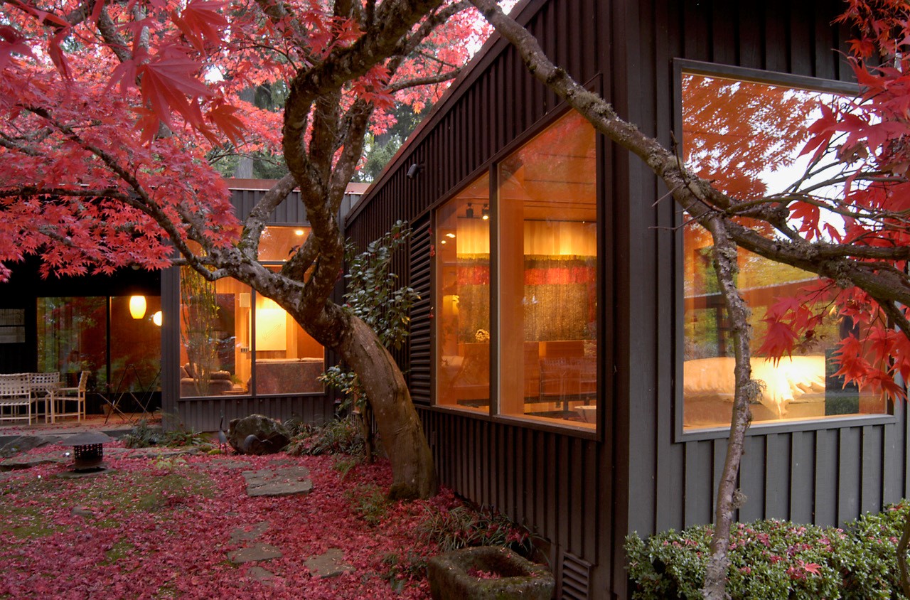 A japanese maple with mature red leaves frames the corner wing of the house.